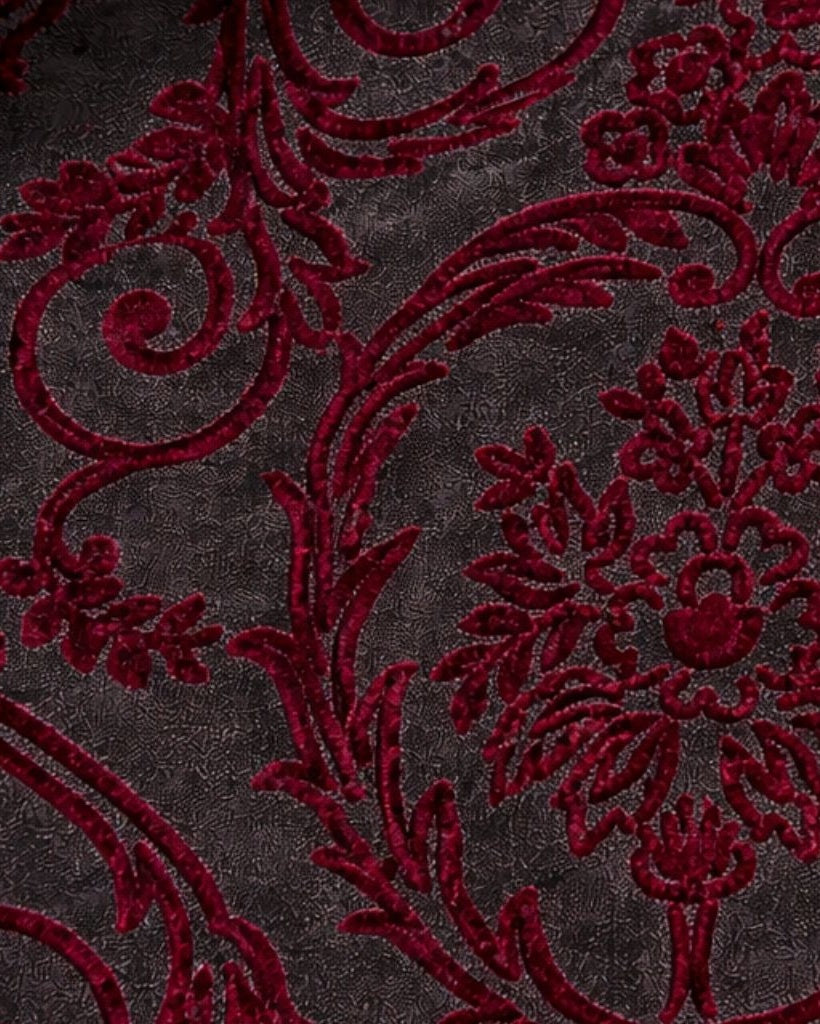 Close-up of the Burgundy Baroque Velvet Graphic Jacket fabric featuring rich burgundy baroque velvet motifs on a textured dark background, highlighting luxurious craftsmanship and intricate detail.