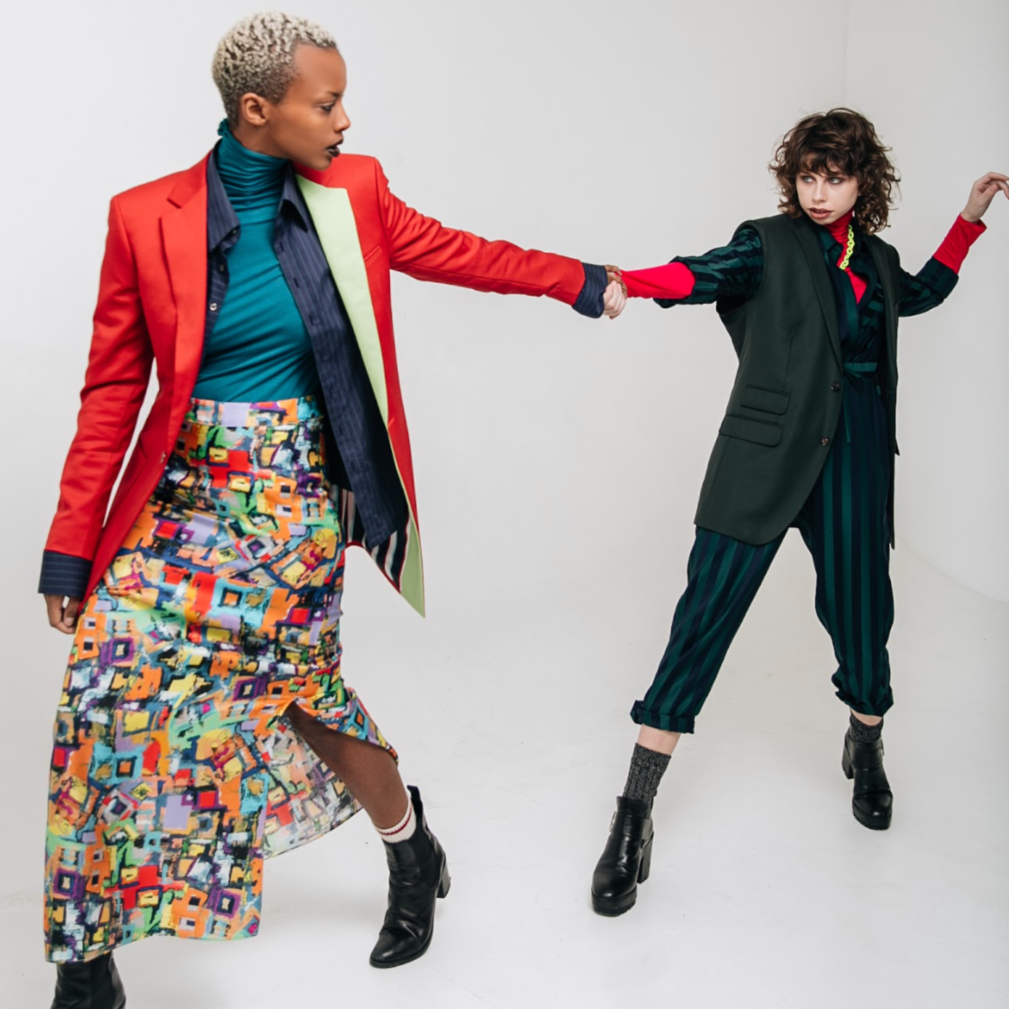 Two women in colorful outfits posing against a white background