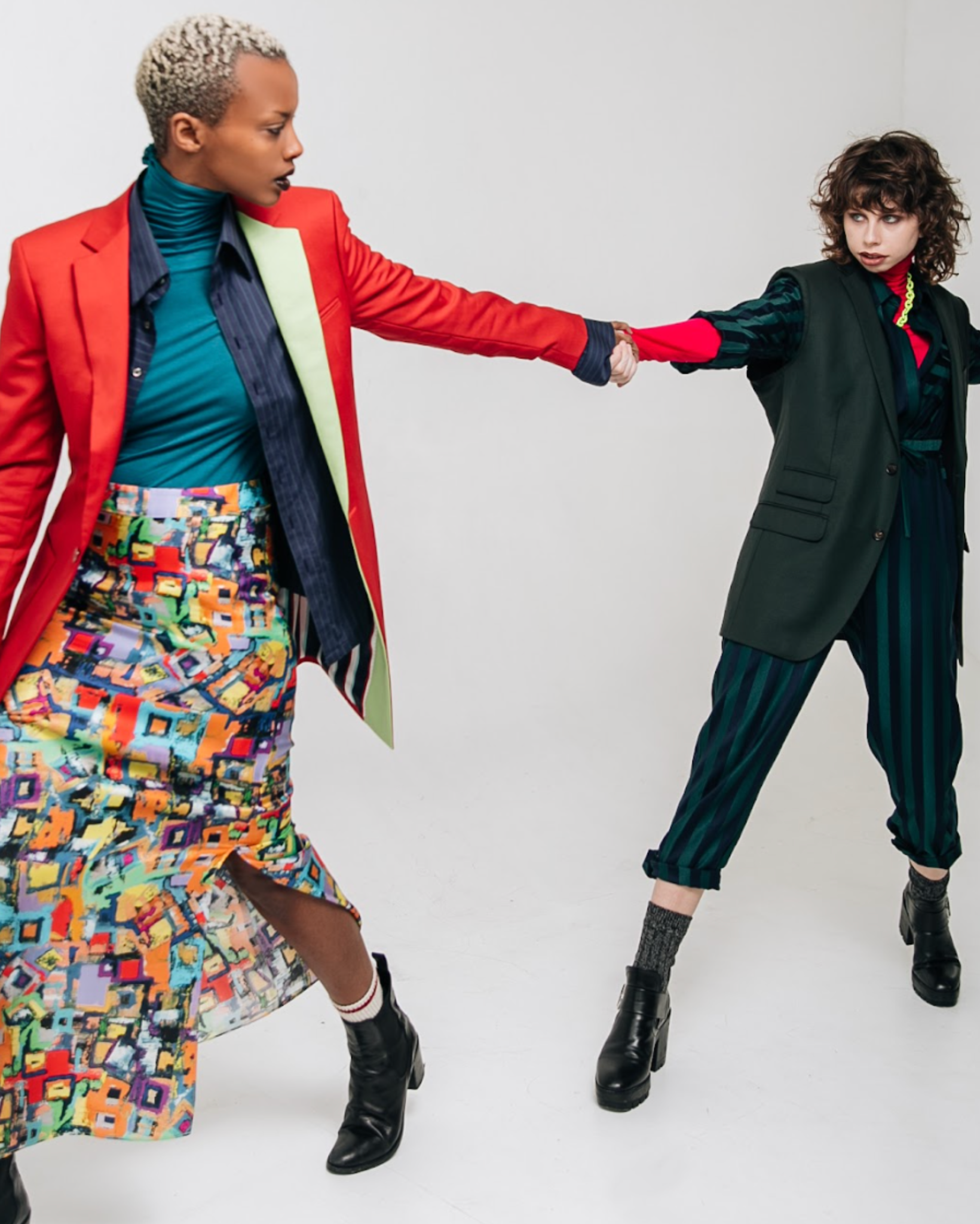 Two women in colorful outfits posing against a white background