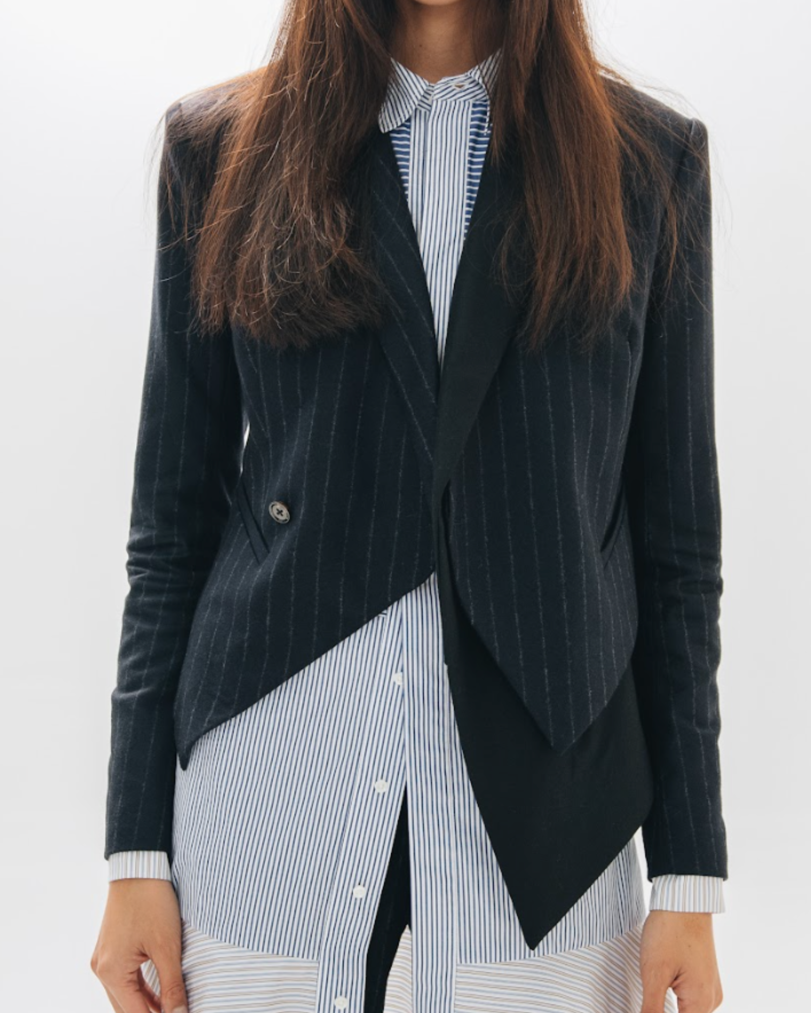 Person wearing a black pinstripe blazer over a striped shirt on a white background