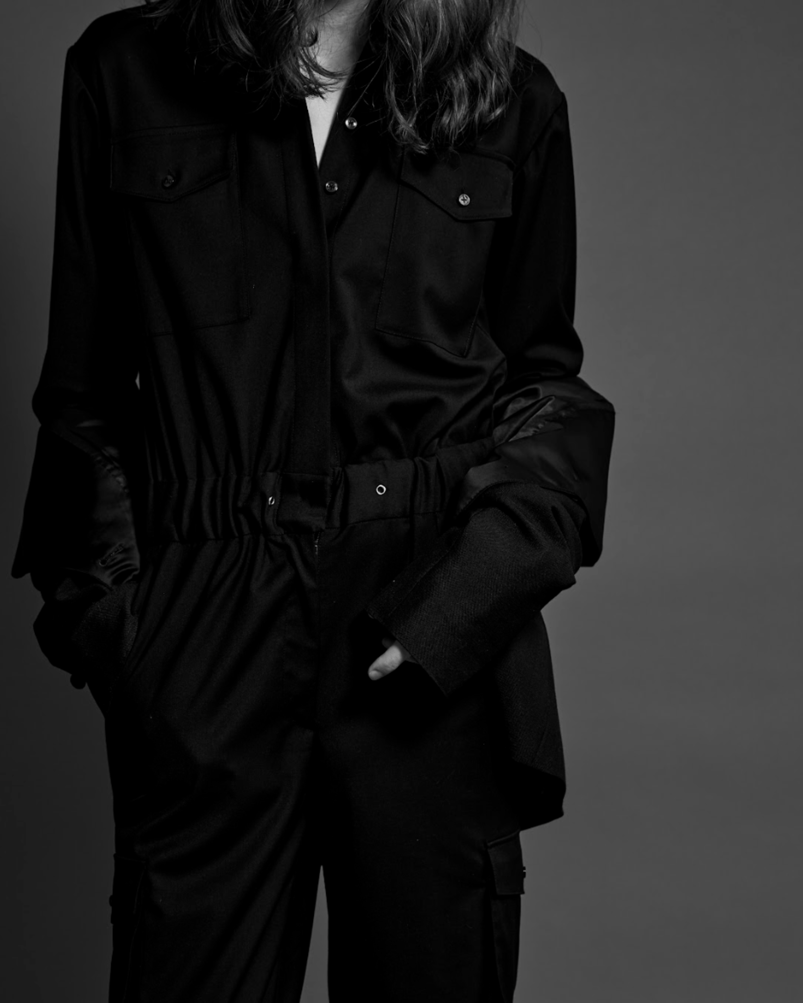 Person wearing a black outfit against a gray background