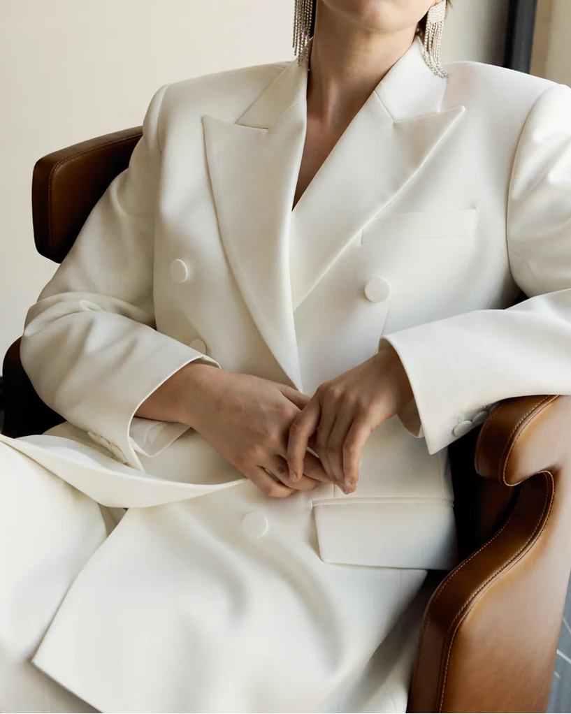 Woman in a white suit sitting in a chair by a window