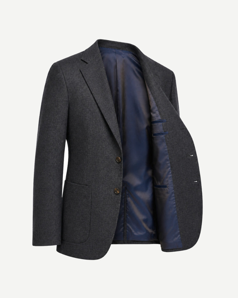 Open three-quarter view of The Wide-Frame Wool Sport Coat in dark charcoal wool, revealing the navy lining, interior pocketing, generous lapel, and relaxed tailored shape.