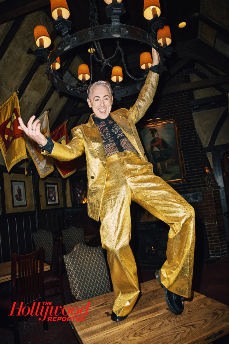Alan Cumming wearing The Tailory New York's Gold Lamé Suit Set during The Traitors filming, showcasing the metallic tailored blazer and trousers that exemplify luxury streetwear's intersection with reality television and gender-fluid fashion expression.