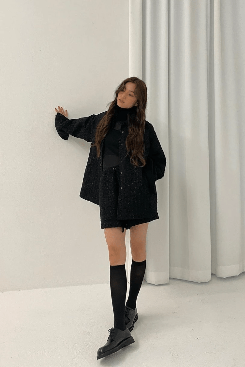 A young woman in an all-black Korean-influenced ensemble