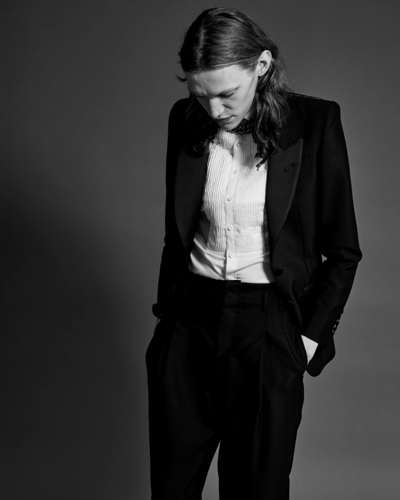 Person wearing a black suit and white shirt against a gray background