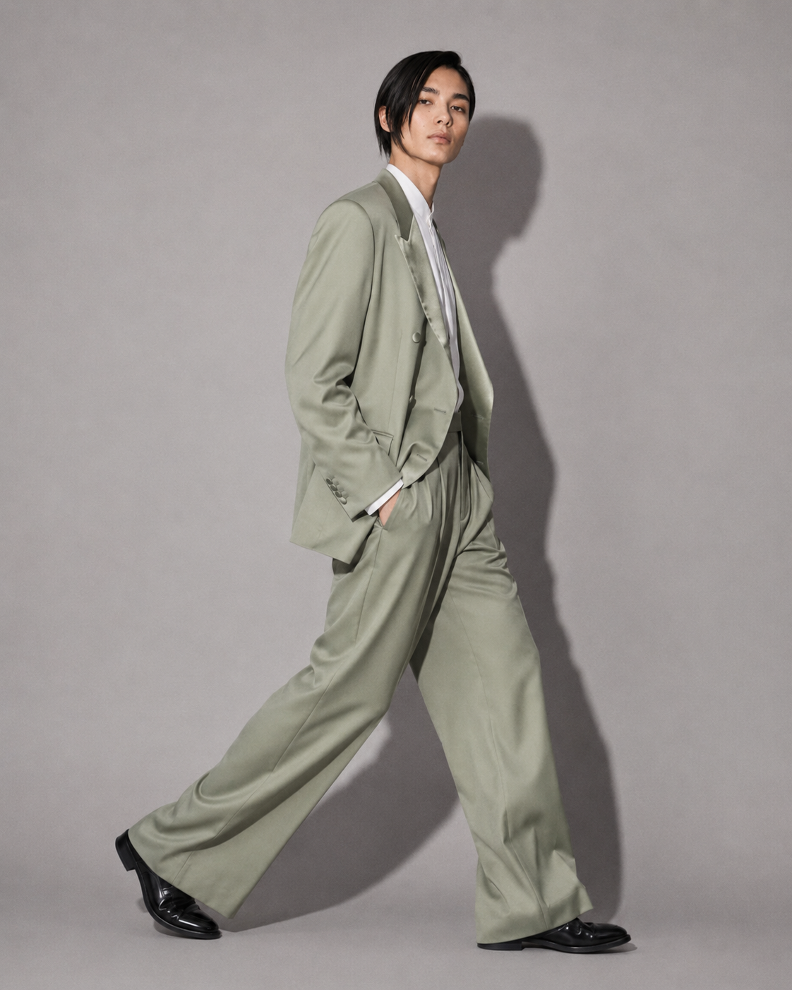 Person wearing a green suit against a gray background