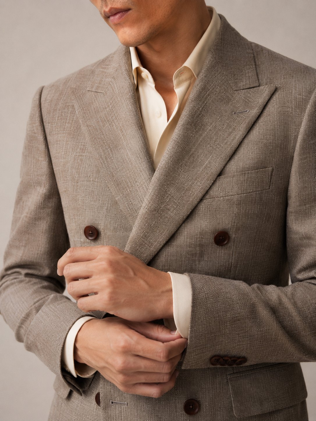 Close-up of a person wearing a beige suit jacket with a plain background