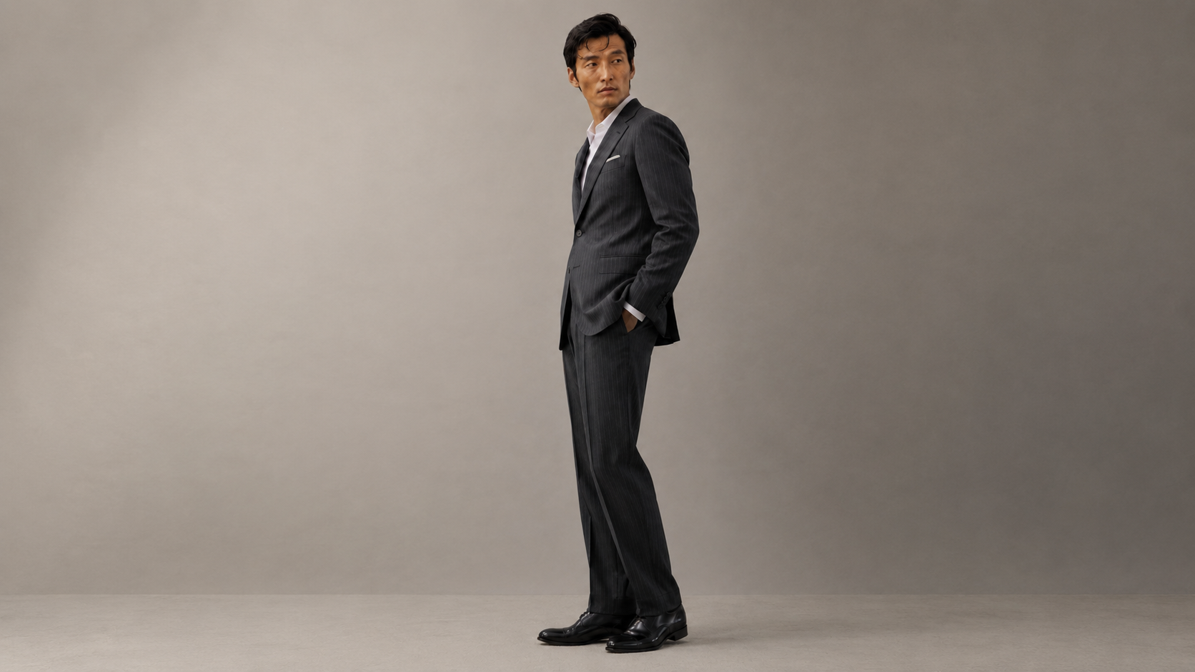 Man in a gray suit standing against a plain background