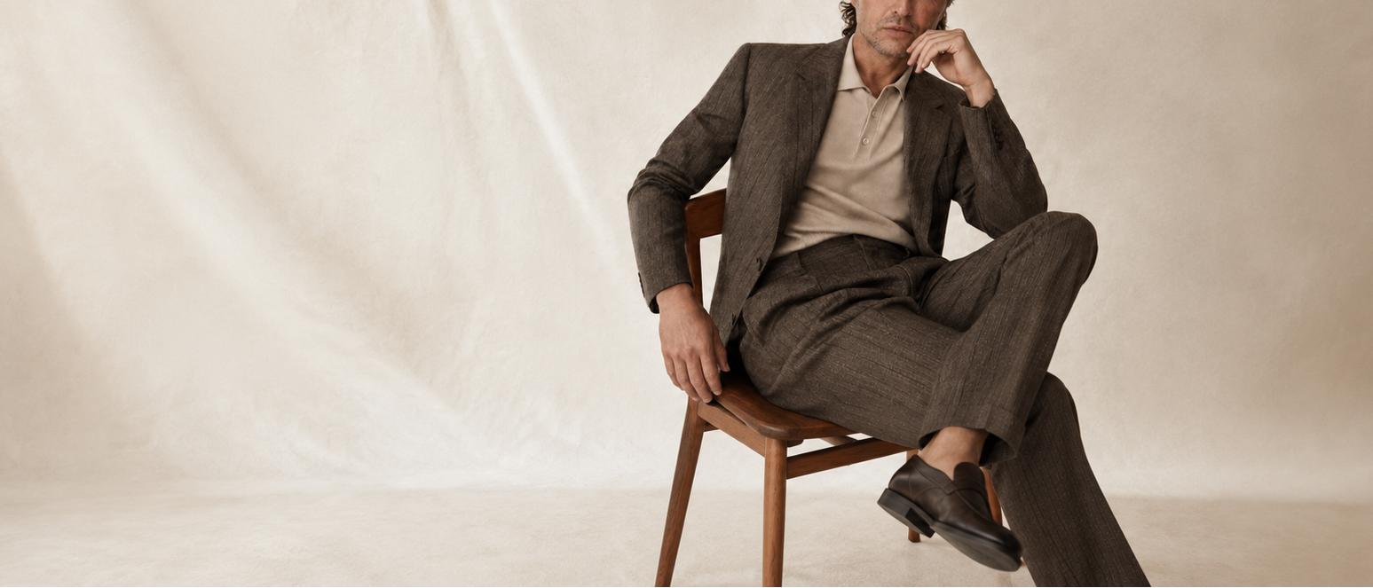 Man in a suit sitting on a chair against a plain background