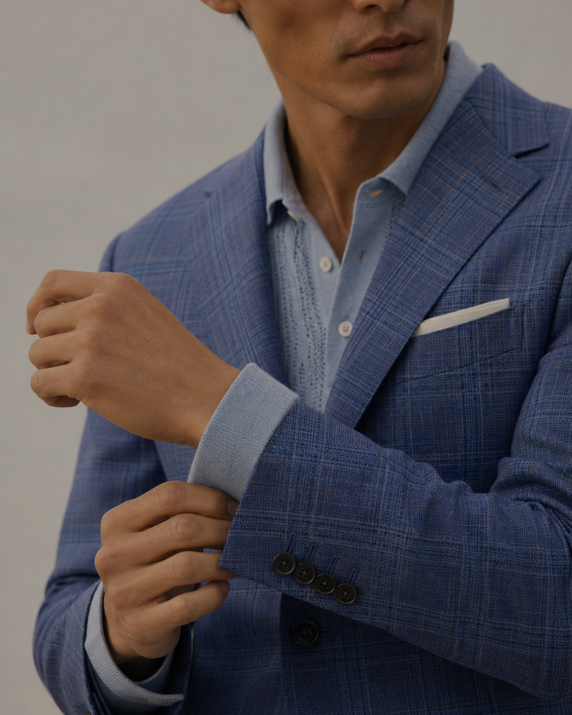 Man wearing a blue checkered suit with a light blue shirt against a neutral background