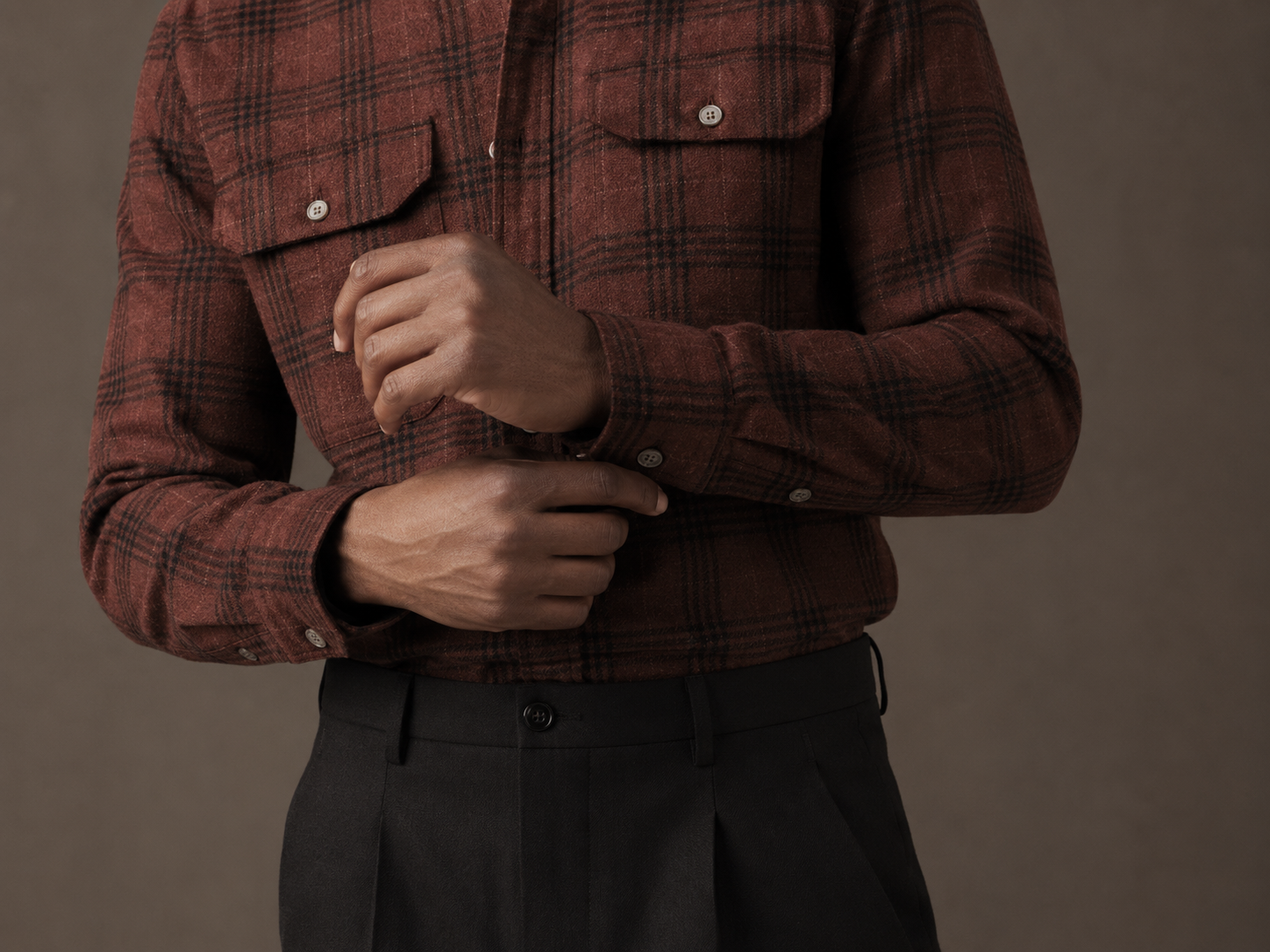 Person wearing a red plaid shirt against a brown background