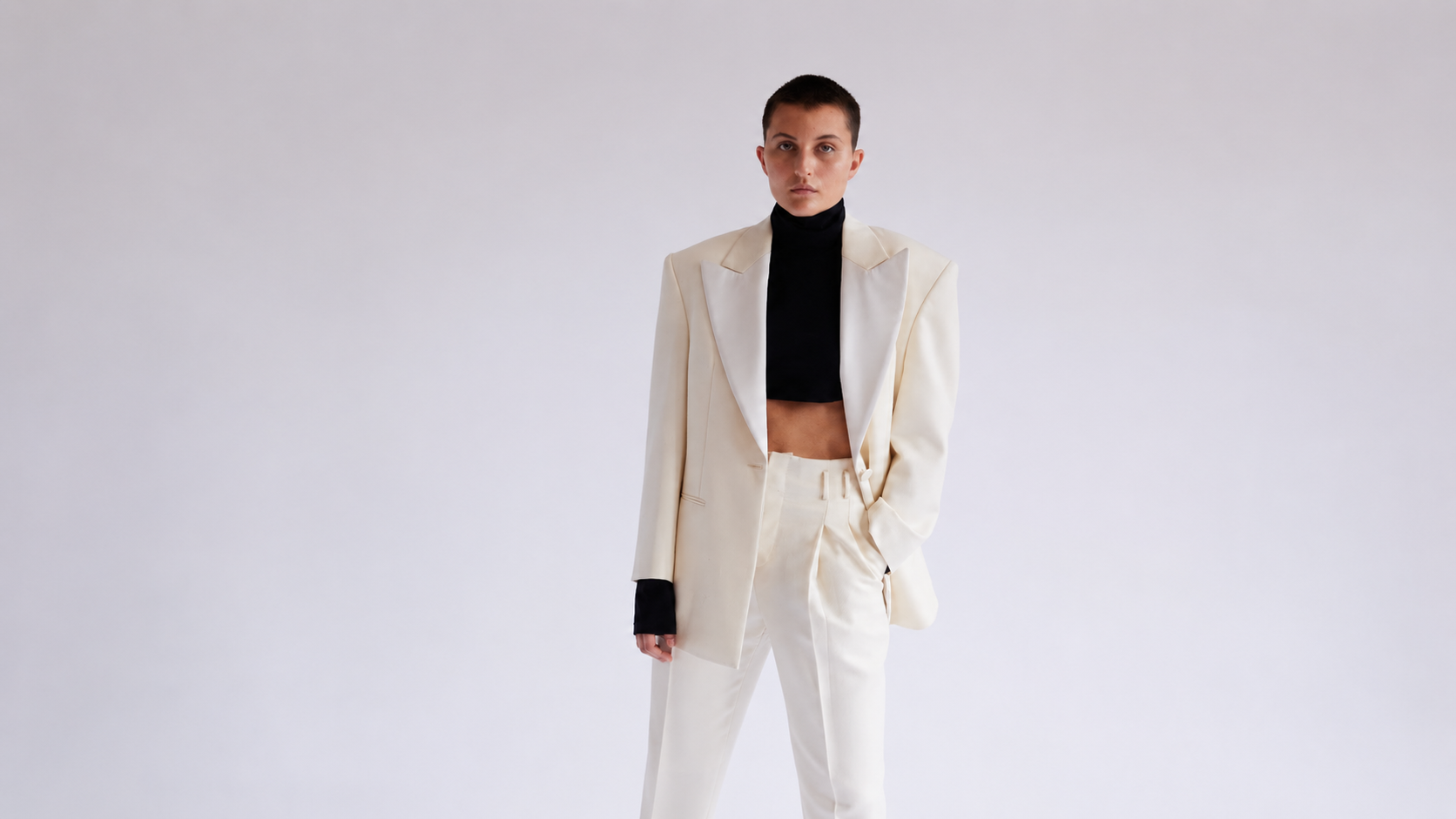 Person wearing a white suit with a black top on a plain background