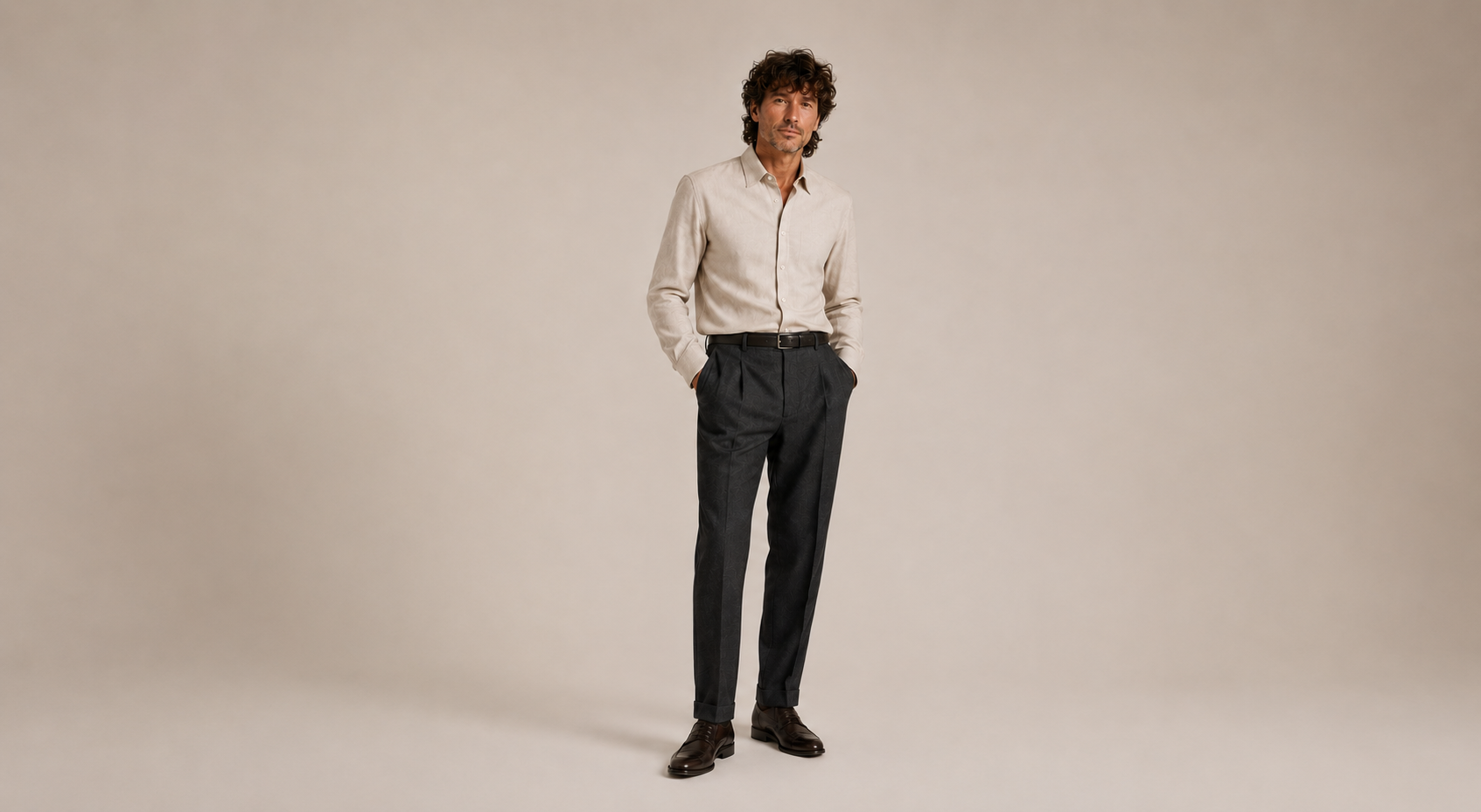 Man wearing a light shirt and dark pants against a beige background