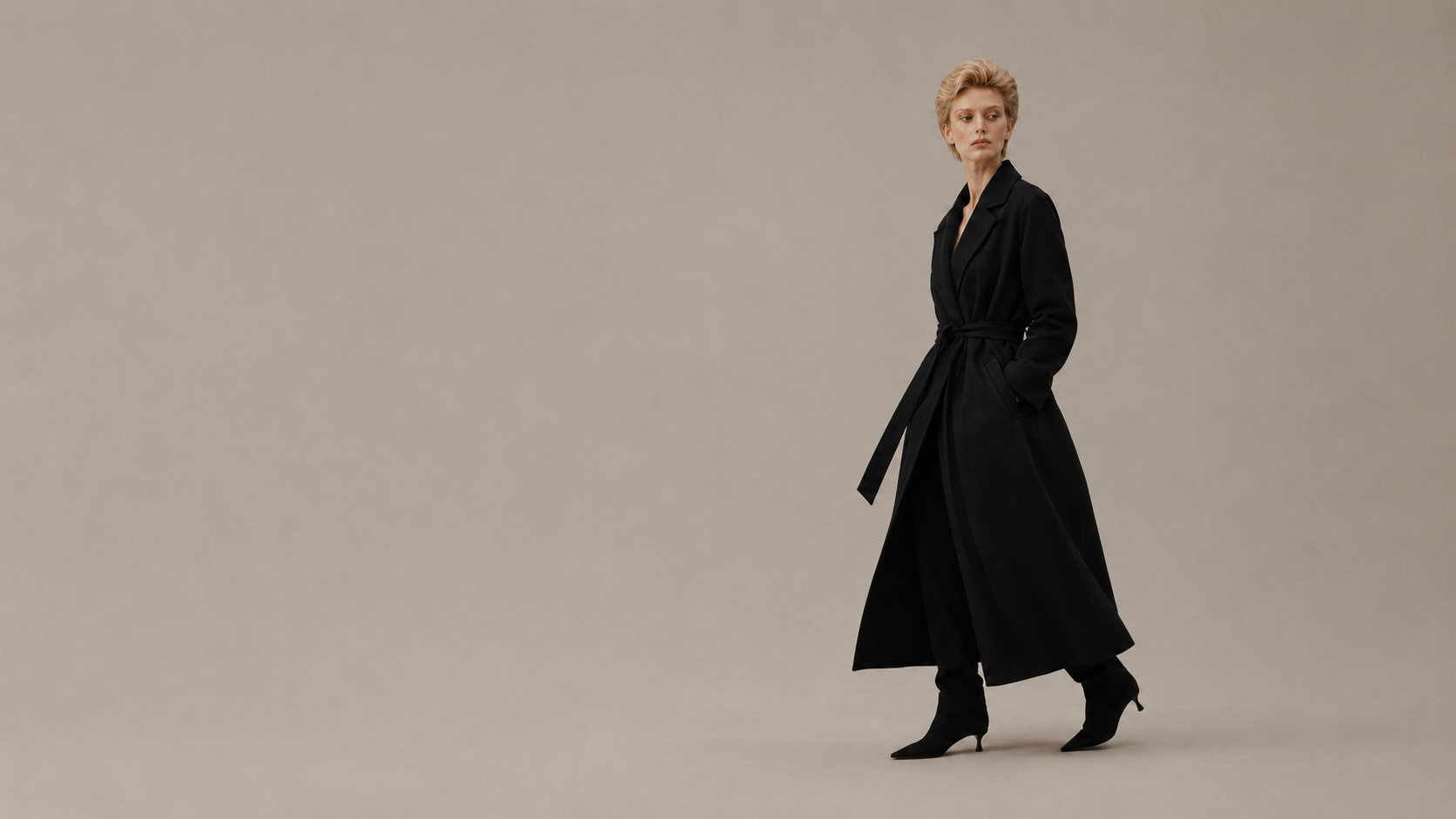 Person wearing a black coat on a beige background