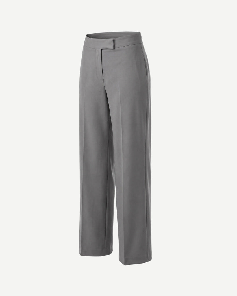 Angled view of The Dailies Wide-Leg Trouser showing the grey suiting fabric, structured waistband, front closure detail, pressed crease, and wide-leg shape.
