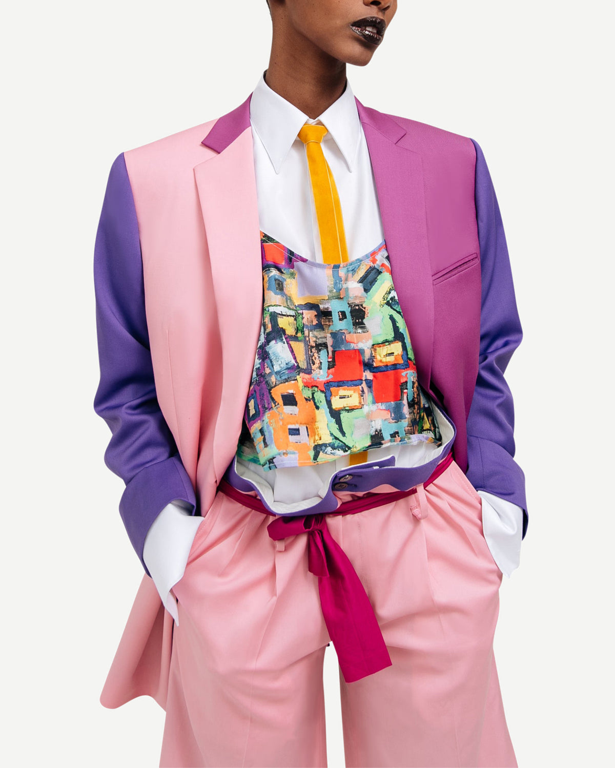 Model wearing the Pink Purple Color-Block Double-Breasted Blazer styled with a vibrant abstract print top and light pink high-waisted trousers, showcasing bold gender-neutral suiting.